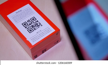 Smart Phone Scanning QR Code In Paper Label On The Orange Package Or Parcel Box