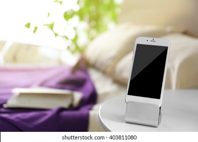 Smart Phone With Stand On A Bedside Table In A Room
