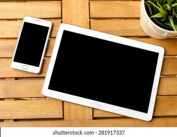 Smart Phone And Tablet Pc With Plant. Smart Phone And Tablet Pc With Green Plant On Wooden Table.