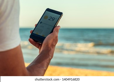 Smart phone with weather forecast on screen, smart phone dialing 29ºC at Matalascañas beach in Huelva, Andalusia, Spain - Shutterstock ID 1404916820