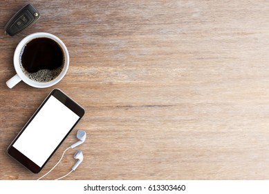 Smart phone,car key and earphone with cup of coffee on wood table. Top view with space for any design.Business concept