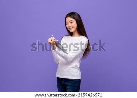 Smart pretty young Asian woman using tablet computer in isolated purple studio background