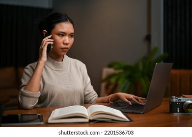 Smart And Professional Asian Female Boss Having A Serious Talk On The Phone With Her Business Partner While Looking Some Details On Laptop Computer.