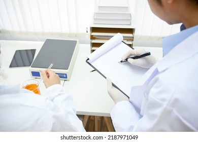 A Smart And Professional Male Scientist Or Medical Technician Working In His Office Lab, Records An Experiment Result On His Clipboard. Close-up Image