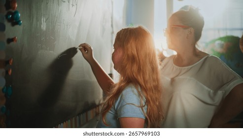 Smart Pupil Showcasing Math Knowledge: Static Shot of Elementary School Girl Solving Mathematical Problems Writing on the Chalkboard in Classroom. Female Teacher Checking Answers, Helping Student.