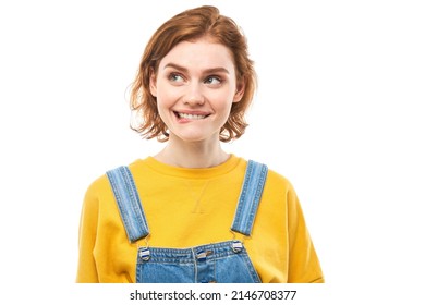 Smart redhead girl in casual grimaces and bites lips thinks doubts, makes decision isolated on white studio background - Shutterstock ID 2146708377