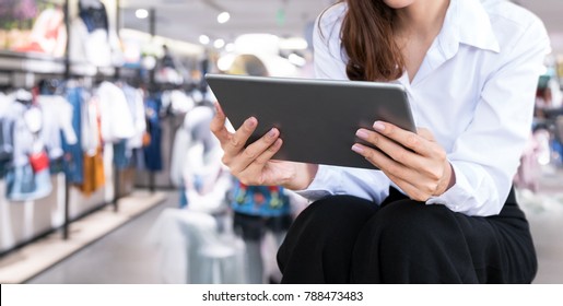 Smart retail internet of things , chatbot , online shopping technology trend concept. Female worker using tablet and blur retail shop background.
