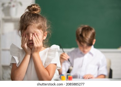 A Smart School Girl Cry. Schoolgirl In Uniform Covering Her Face With Her Arm Crying Sad Of Bullying At School Standing In Front Of Blackboard. Childhood And Education Problem Concept.