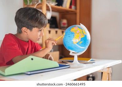 Smart Schoolboy Doing Homework At The Desk Use School Supplies And A Globe For Geography Exercises. Back To School. - Powered by Shutterstock