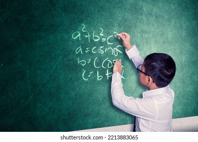 Smart Schoolboy Solving Math Problem On The Chalkboard While Standing In The Front Of Class