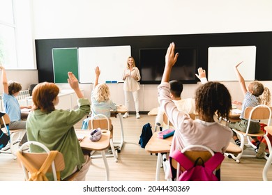 Smart schoolchildren classmates students pupils listening to the teacher at lesson class raising their hands. Excellent marks. Attendancy, academic performance concept