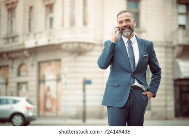 Smart Senior Business Man, An Elderly Entrepreneur And Business Owner, Talking Over His Cell Phone In An Outdoors Urban Area