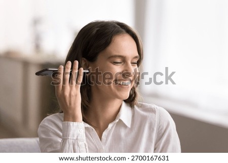 Smart speaker technology. Head shot smiling young lady hold phone flat by ear listen to voice note casual podcast music track audiobook via loudspeaker get ai assistant response to given vocal command