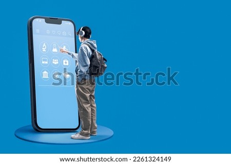 Smart student using a big smartphone with online education app interface, he is choosing a subject, e-learning concept