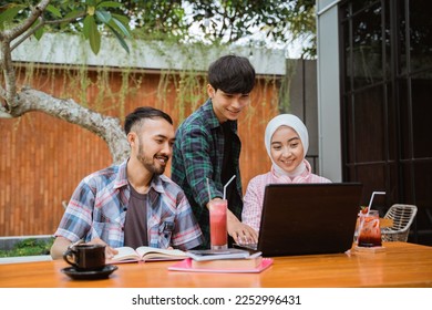 Smart students studying together with a laptop and books in outdoor cafe - Powered by Shutterstock