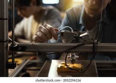 Smart students using a 3D printer and a laptop, engineering and prototyping concept