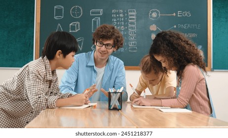 Smart teacher explain idea while diverse children drawing mind map while group of diverse student working together to do class work. Attractive instructor teaching and talking about working. Pedagogy.