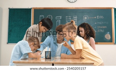 Smart teacher explain idea while diverse children drawing mind map while group of diverse student working together to do class work. Attractive instructor teaching and talking about working. Pedagogy.