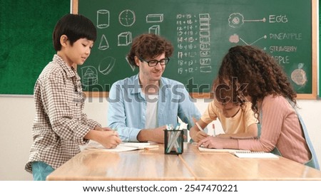 Smart teacher explain idea while diverse children drawing mind map while group of diverse student working together to do class work. Attractive instructor teaching and talking about working. Pedagogy.