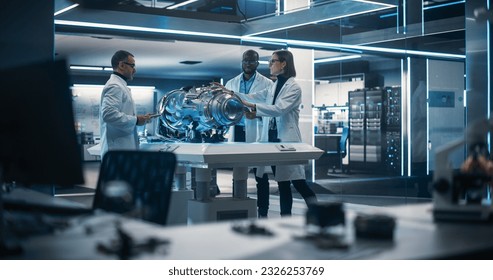 Smart Team of Engineers, Project Manager and Machinery Operators Collaborate on a New Type of a Electric Turbine Engine, Standing with Tablet and Laptop Computers in Scientific Technology Laboratory