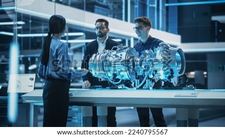 Smart Team of Engineers, Project Manager and Machinery Operators Collaborate on a New Type of a Electric Turbine Engine, Standing with Tablet and Laptop Computers in Scientific Technology Lab.