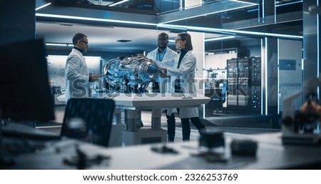 Smart Team of Engineers, Project Manager and Machinery Operators Collaborate on a New Type of a Electric Turbine Engine, Standing with Tablet and Laptop Computers in Scientific Technology Laboratory
