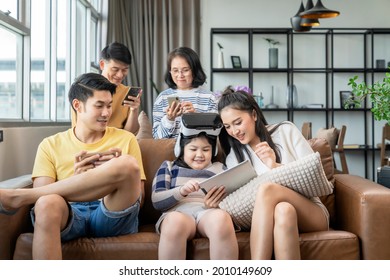 Smart Technology With Lifestyle At Home,asian Generation Family Enjoy Technology Device Hand Use Smartphone Tablet And Vr Goggle Glasses Play Fun Together On Sofa Living Room At Home Quarantine Moment