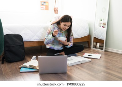 Smart teen girl reading her academic books in her bedroom. Caucasian adolescent girl having breakfast cereal while studying for her exams - Powered by Shutterstock