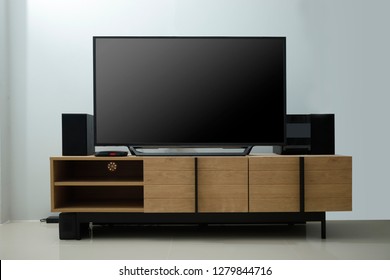 Smart Tv With Black Glossy Screen On Console Wood In Living Room.