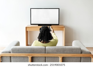 Smart TV in minimal living room. Woman relaxing at living room by watching TV. Woman sitting on couch and watching TV. Woman using smart TV at home.  - Powered by Shutterstock