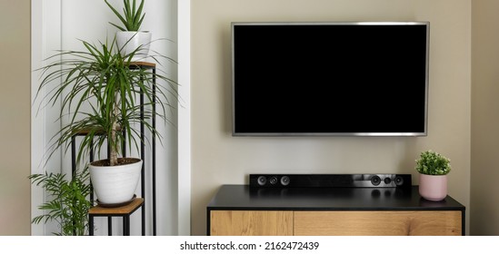 smart tv mockup hanging on beige wall in modern interior with green plants - Shutterstock ID 2162472439