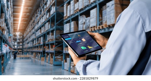 Smart Warehouse,Inventory management system concept.Manager using digital tablet,showing warehouse software management dashboard on blurred warehouse as background