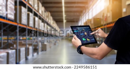 Smart Warehouse,Inventory management system concept.Manager using digital tablet,showing warehouse software management dashboard on blurred warehouse as background