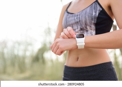 Smart watch for sport. Athlete wearing heart rate monitor. Runner looking at sports smartwatch going running outside. Female athlete tracking her activities using wearable technology.