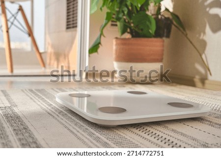 Smart weight scale on a patterned rug in a bright room promoting health and wellness