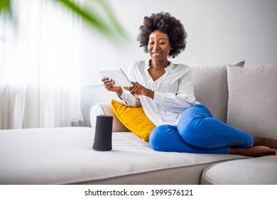 Smart wireless column with a young woman controlling home devices with a voice commands on the background at home. Woman controlling home devices with a voice commands  - Powered by Shutterstock