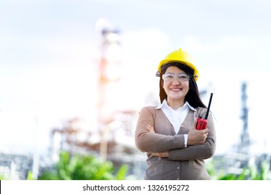 Smart Woman Engineer Standing Outside Petrol Plant With White Helmet And Electronic Radio. Communicate With Her Team To Maintenance Security Processing Around Factory And Prevent Accident 