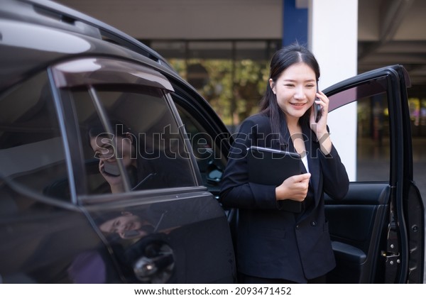 Smart working women having a business talk on\
the phone while getting out of the\
car.