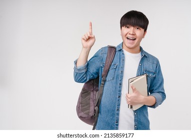 Smart young asian korean man student high schoolboy holding textbooks and notebooks, carrying a bag, going to university school college having idea, pointing at copyspace isolated in white - Powered by Shutterstock