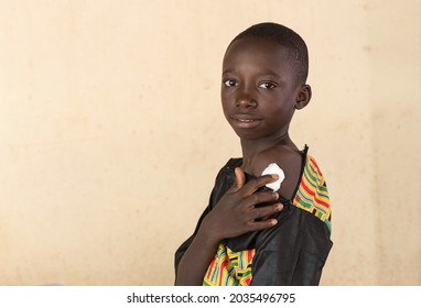 Smart Young Black African Boy Pressing A Disinfecting Cotton Ball On The Injection Site On His Left Arm; Covid-19 Vaccination Concept