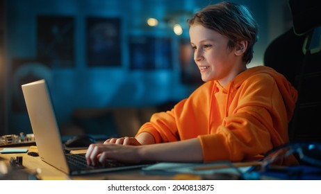 Smart Young Boy Making A Video Call On Laptop Computer In Cozy Dark Room At Home. Happy Teenager Attending Online Class, Chatting With Friends, Studying School Homework.