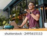 Smart young caucasian business man freelancer it worker guy manager male student recording voice message talking on mobile smart phone with customers partners while working studding in office cafe