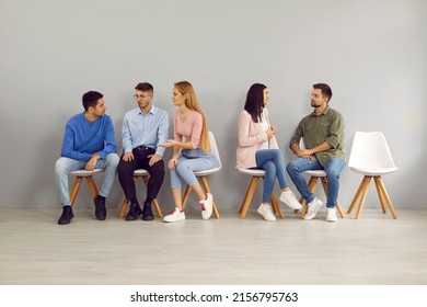 Smart young people sit in line for interviews and communicate with each other sharing experiences. Candidates sit on chairs in waiting room and talk before hiring process. Employment concept. - Powered by Shutterstock