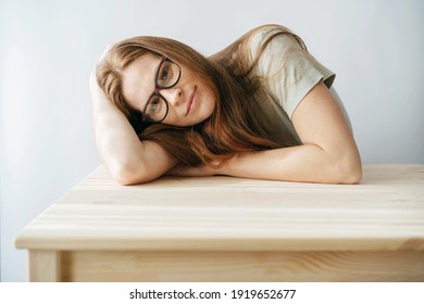 Smart Young Redhead Freckled Woman With Glasses Leaning On Her Arms While Sitting At The Table. Portrait Of A Candid Woman.