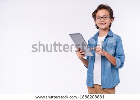 Smart young white boy using tablet in casual outfit isolated over white background