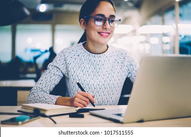 Smart young woman satisfied with learning language during online courses using netbook, smiling female student doing homework task in college library searching information via laptop computer