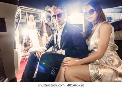 Smartly dressed celebrity couple, ready to get out of a limousine during a red carpet event, with several paparazzi and tabloid photographers waiting for them. - Shutterstock ID 481445728