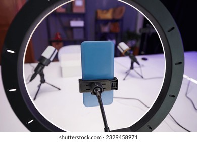 Smartphone attached to ring light in studio of beauty blogger