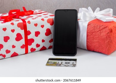 Smartphone with a bank card and Christmas gifts on the table. Online shopping festive internet concept.