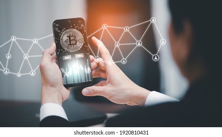 Smartphone with Bitcoin chart on-screen among piles of Bitcoin concept. businessman touch on mobile app screen with big BUY and SELL buttons on the stock market, Cryptocurrency and finance.